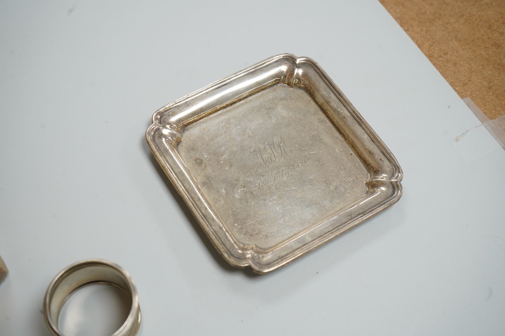 A George VI silver mounted rectangular cigarette box, Atkin Brothers, London, 1944, 17.3cm, together with a small silver dish, William Comyns & Sons Ltd, London, 1945, an Edwardian silver napkin ring and a George III sil